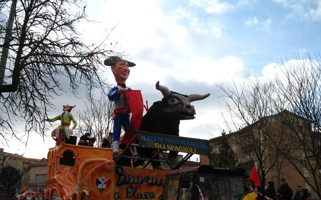 Un carro allegorico in cartapesta con un torero e un grande toro sfila tra il pubblico al Carnevale di Tempio Pausania