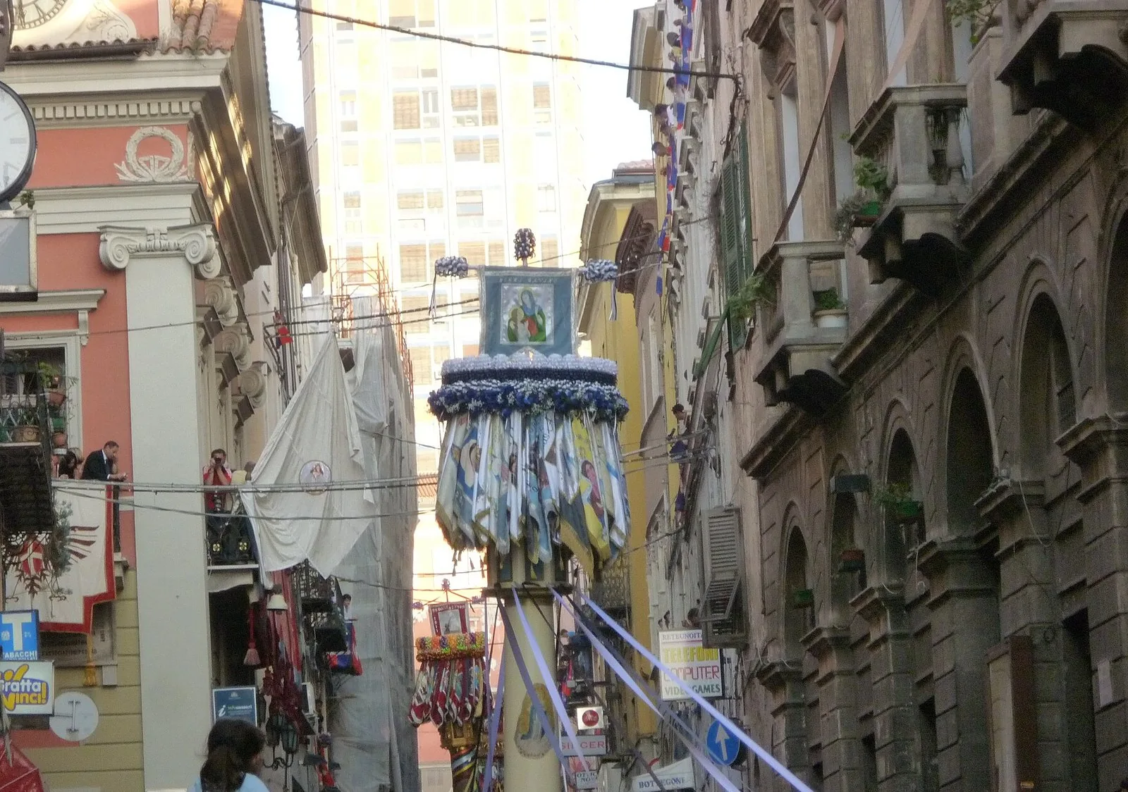 Un candeliere ornato di nastri e bandiere avanza tra la folla in una via del centro di Sassari durante la Discesa dei Candelieri