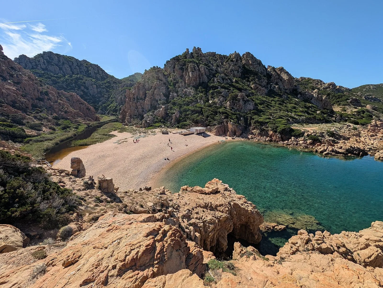 La caletta di Li Cossi a Costa Paradiso vista dall'alto, con acqua turchese, sabbia chiara e rocce di granito rosa, con pochi bagnanti