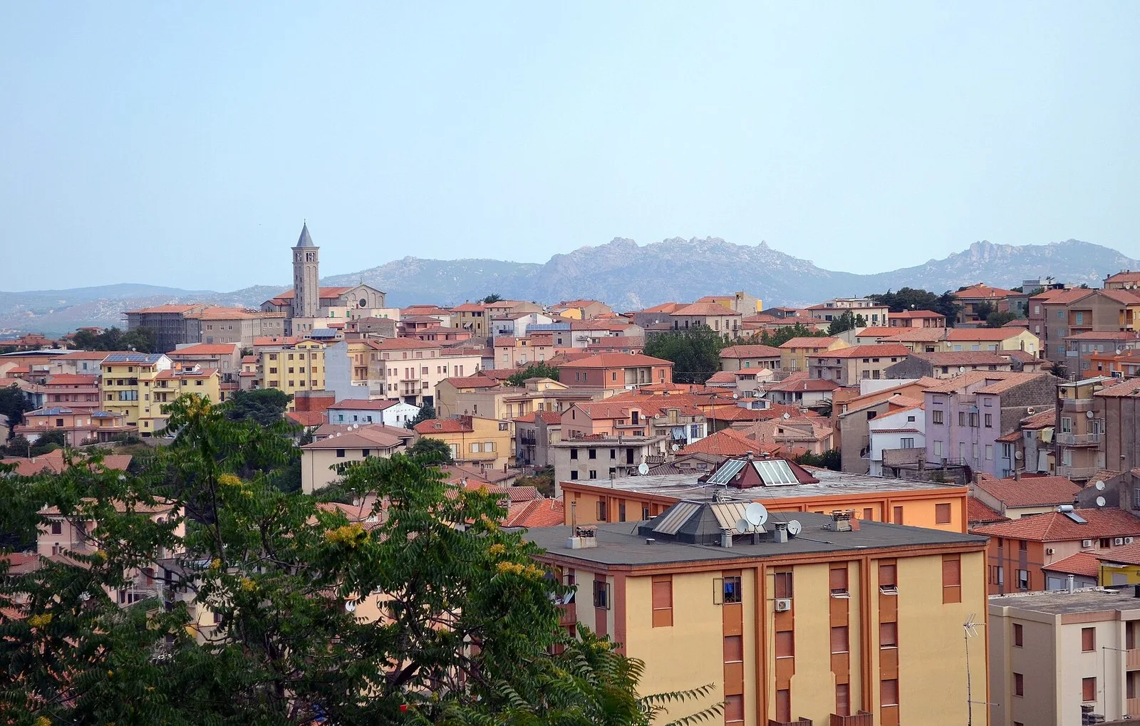Veduta di Tempio Pausania con i tetti del paese, un campanile e le montagne di granito sullo sfondo
