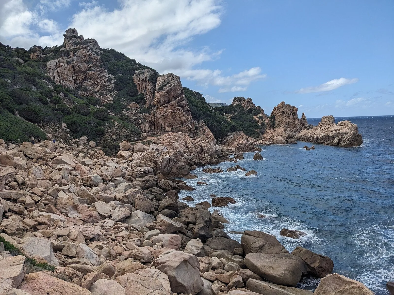 Costa rocciosa di granito rosato lungo il sentiero per la spiaggia di Li Cossi, a Costa Paradiso, con il mare mosso